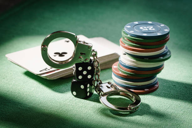 Gambling ban concept. Dice, cards and handcuffs on the table in hard light